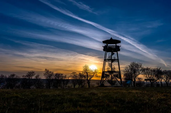 Bir gözetleme kulesi olan manzara ve gün batımında arka planda kırmızılar.