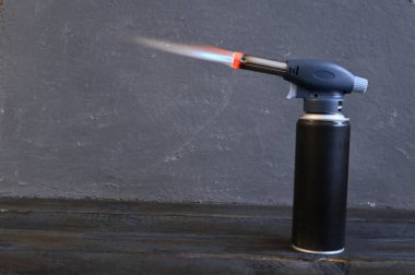 Gaz lehimleme demirinin başlığından çıkan ateş turist gaz silindirine konmuş. Yüksek kalite fotoğraf