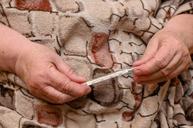 the thermometer is in elderly hands.