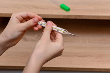 mercury thermometer in hand. temperature measurement. close-up