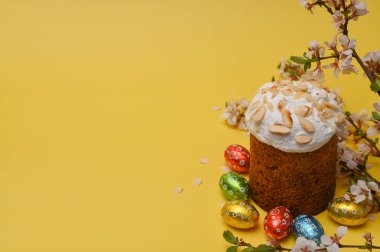 Sarı arka planda yumurtalı geleneksel Paskalya tatlı ekmeği. Fındıklı şekerli paskalya pastası. Paskalya hediyesi, bayram sembolü. Boşluğu kopyala. 