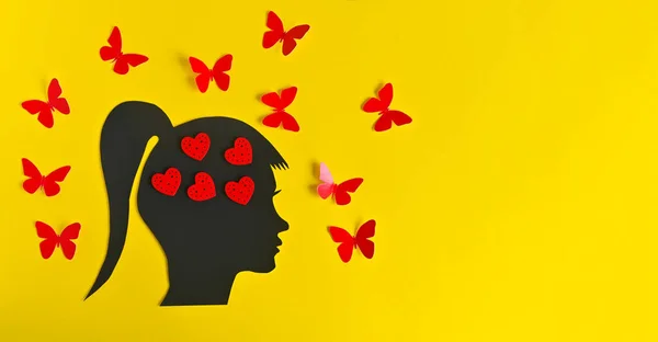 Silhouette of a woman's head with hearts in the brain and butterflies around. banner on a yellow background. the concept of a happy girl dreaming and thinking about love. copy space, Layout