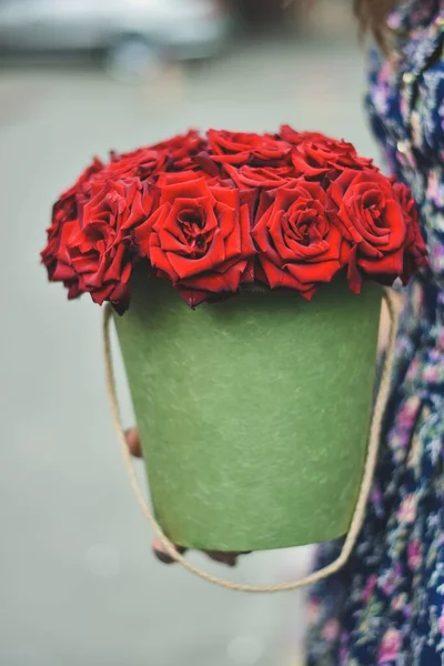 a bucket with red roses in his hands