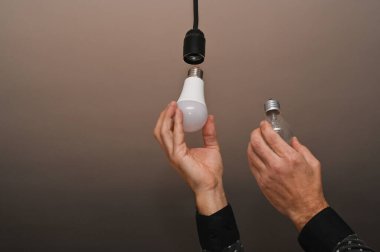 Ellerinde iki lamba, LED ve parlak ışık. Enerji tasarrufu kavramı.