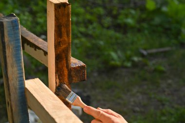 Ahşap çitler için tahta kirişleri boyayan bir adam.