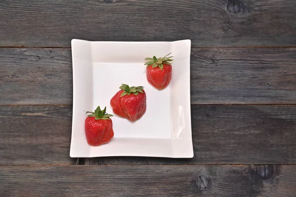 Drei Erdbeeren Einem Schönen Weißen Teller Auf Einem Hölzernen Hintergrund — Stockfoto