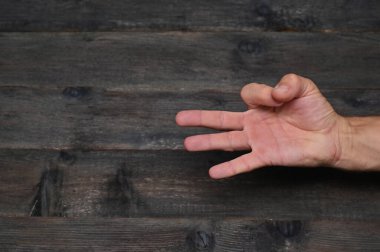 Ahşap arka planda parmaklarını gösteren adamın eli 3 numarayı gösteriyor..