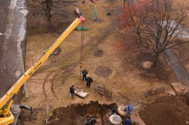 Eski kanalizasyon borularını değiştirirken tesisatçıların işi. Kamyon vinçle kaldırma işi. Kharkiv bölgesi, LOZOVAYA, UKRAINE - 23 Aralık 2022. Editör fotoğrafı