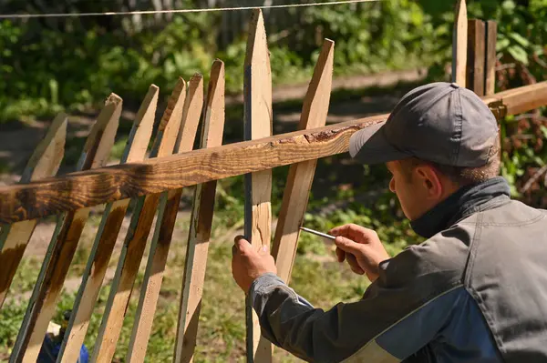 a carpenter marks out boards for making a fence in the garden.
