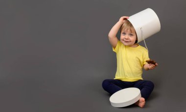 Küçük bir kız oynarken gülüyor. Gri bir arka planda. Kafasına bir kutu koydu. maket yap