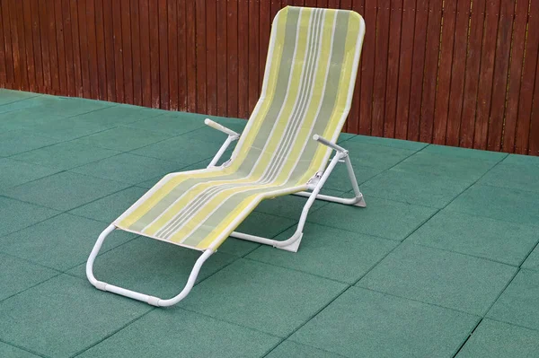 One empty deck chair or chaise longue. Concept of recreation, tanning in yard on sunbed.