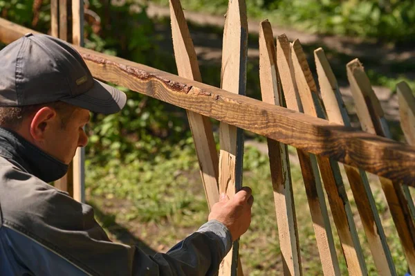 a master carpenter makes a wooden fence