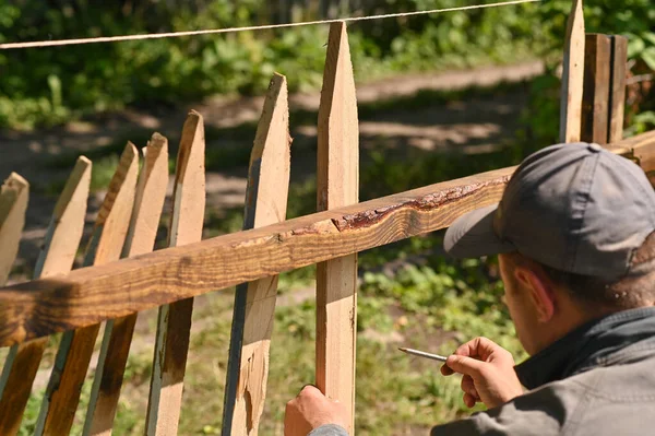 A man master builds a fence. arranges and makes notes with a pencil.