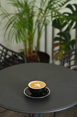 Masanın üzerinde kalp şeklinde latte ile servis edilen siyah kapuçino.