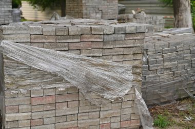 Gri tuğlalar küplere istiflenmiş. Depo tuğlalarında beyaz tuğla blokları var.. 