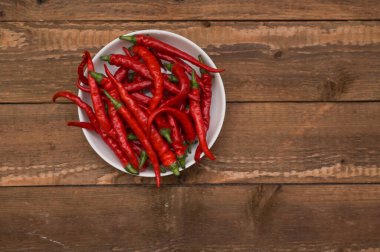 Kırmızı biberle dolu bir tabak. Tahta bir masada..