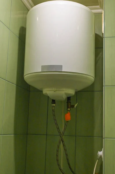 An electric boiler on a green wall.