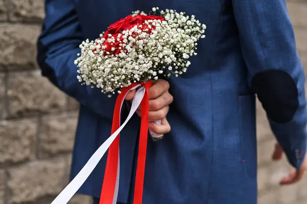 A man holds flowers behind his back