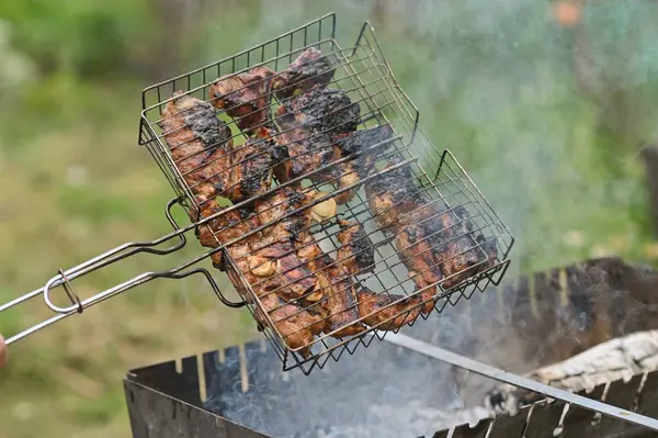 cooking meat in a grill on coals with smoke.
