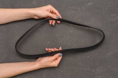 Bir kadının elinde araba jeneratörü kayışı.