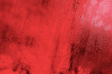 Damlalar camdan aşağı akıyor. kırmızı arkaplan