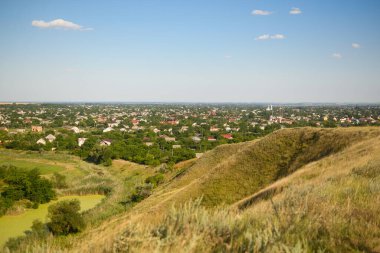 Tepe çimenli bir yokuştur. Evin uzak manzarası