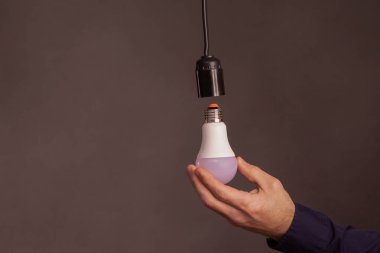 Ellerinde bir LED ampul. 