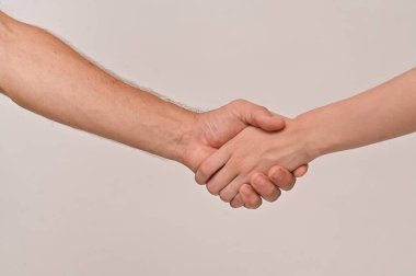 Beyaz bir arka planda erkek ve kadının el sıkışması. Bir adam genç bir kadınla tokalaşıyor..