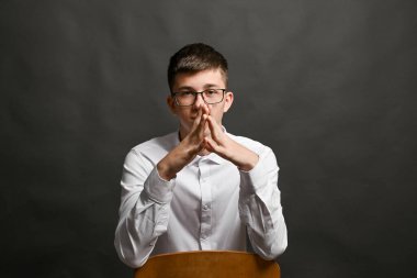 Genç lider bir çan kulesi jestinde ellerini kavuşturdu. Güven ve üstünlük kavramı. Gri bir arkaplanda