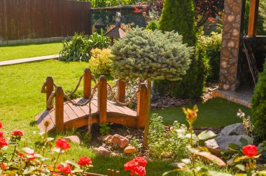 Bahçede, yeşil çimlerin üzerinde tahta bir köprü.