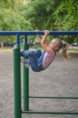 Düz olmayan parmaklıklarda bir kız oynuyor. Aktif eğlence ve spor konsepti