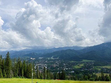 Dağdan çimen ve ağaçlarla uzak bir şehir görebilirsin. tatras - Polonya, 