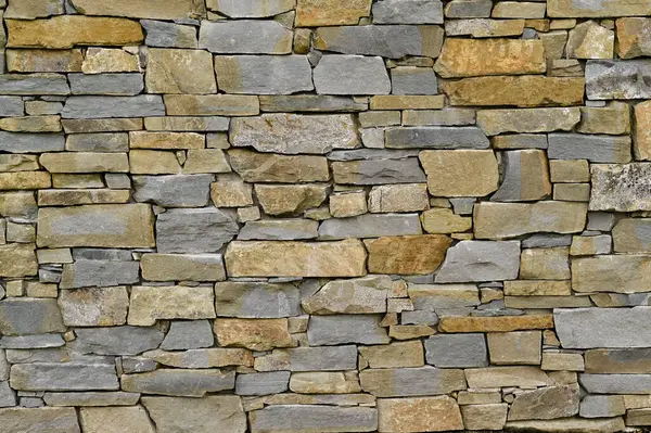Farklı şekillerde taşlardan yapılmış tuğla bir duvar. arkaplan
