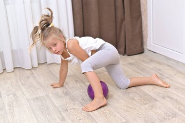Evde küçük bir kız top oynuyor.