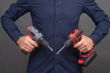 Bir adam iki kablosuz tornavida tutuyor..