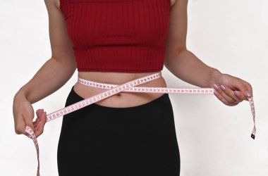 İnce, genç bir kadın belini ölçer. Kilo kaybı,