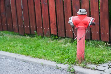 Tahta bir çitin yanında kırmızı bir yangın musluğu..