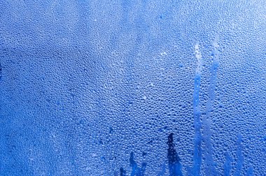Background condensation of water on the window glass due to high humidity. the gradient of the blue background of wet glass.