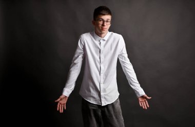 Gri arka plandaki genç adam kollarını açıp avuçlarını kaldırıyor.. 