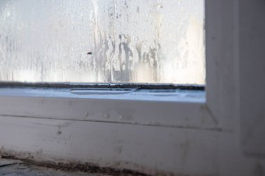 Plastik bir pencerenin camından su damlıyor.