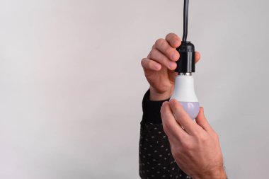 LED lamba bir adamın elinde. Beyaz bir arka planda. Enerji verimliliği kavramı, elektrik faturalarından tasarruf.