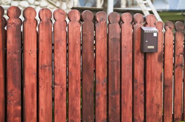 Tahta bir çitte bir posta kutusu asılı.