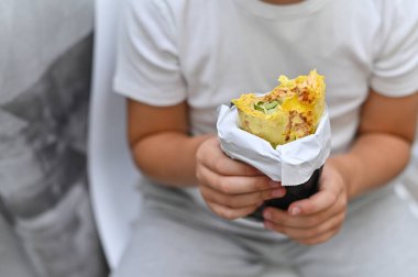 Shawarma bir çocuğun ellerinde. Lavaşlı yemek.