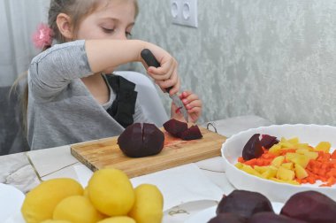 Küçük kız masada salata kesti.