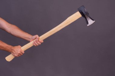 Bir adamın eli odun kesmek için baltayı tutuyor..