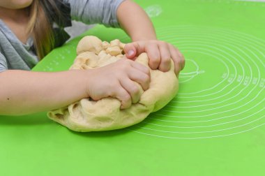 Çocuk fırıncısı mutfak masasında öğreniyor. Dağınık mutfak anı çocukluk aşçılığını merak ve beceri geliştirmeyi yakalıyor. Küçük kız mutlu bir şekilde parayı karıştırıyor. 