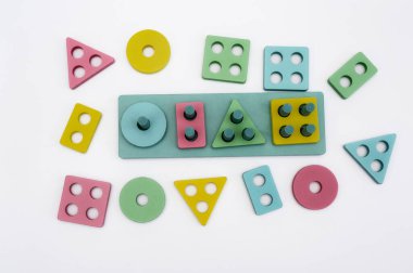 Geometrik şekilli, delikli ve beyaz arka planda duran tahta bir Montessori oyuncağı. Oyun, çocuklar için şekil tanımayı, iyi motor becerileri ve yaratıcı öğrenmeyi teşvik eder.