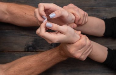 Erkeksi eller kadının ince bileklerini şiddetle kavrıyor. Buna zorla alıkoyma denir. Yırtıcı tutuş çelik kelepçeler gibi iki bileği de sarar. Acımasız kavrama, erkeklerin kadınlara olan saldırısını simgeliyor.