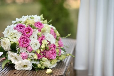 Düğün buketi pembe ve beyaz güller açık hava bankında dururlar. Düğün ayrıntıları romantizmi çağrıştırır, güzellik. Gelin için güzel bir buket çiçek. Aşk ve romantizm kavramı
