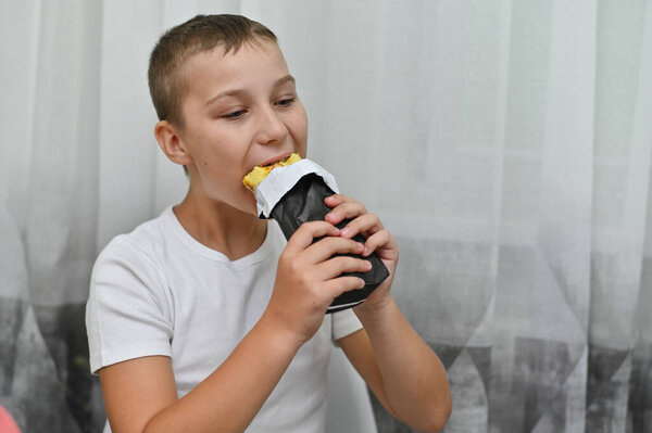 Мальчик кусает булочку с удовольствием.